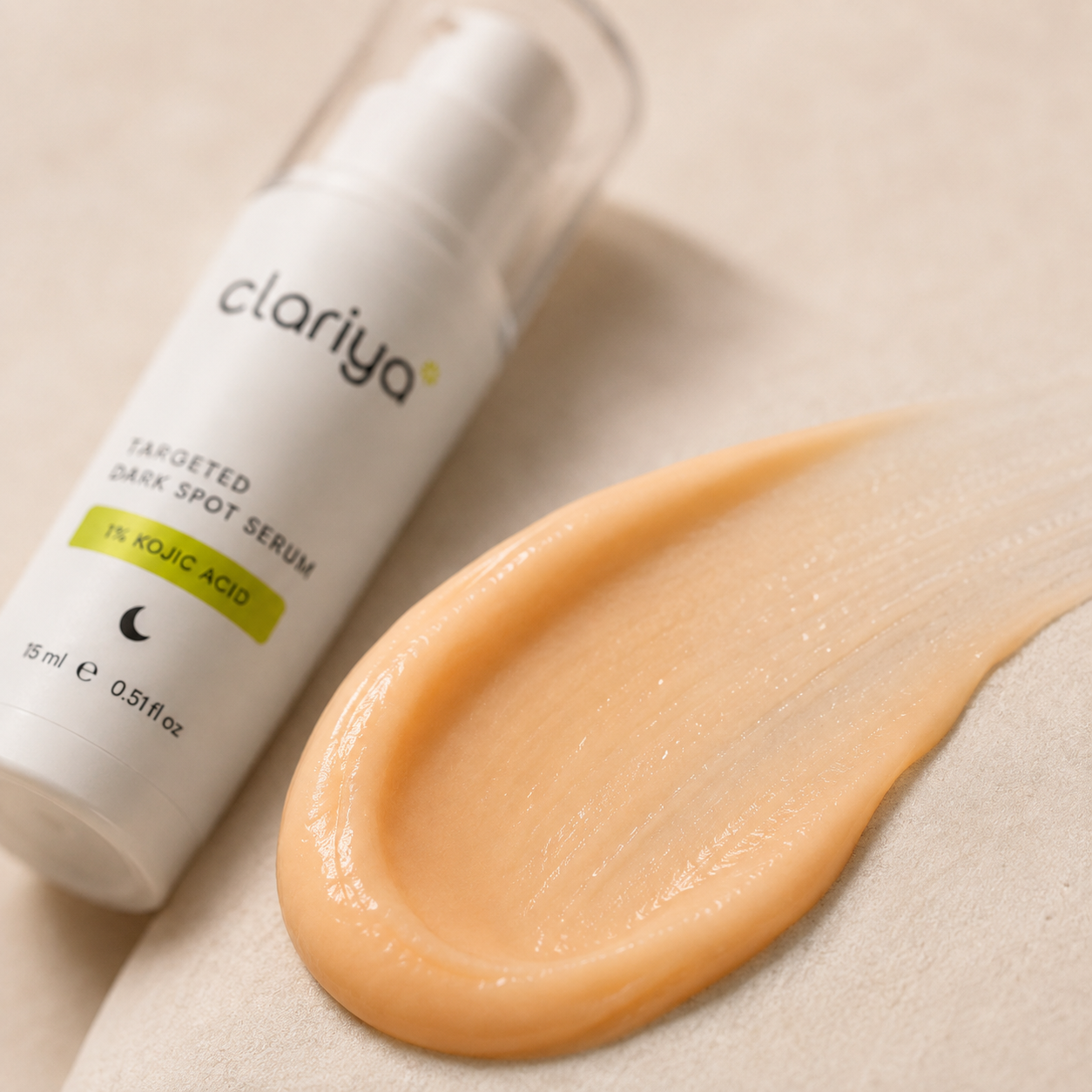 Macro close-up of the peach-to-apricot creamy CLARIYA serum swiped on a soft surface, with the bottle softly blurred behind.
