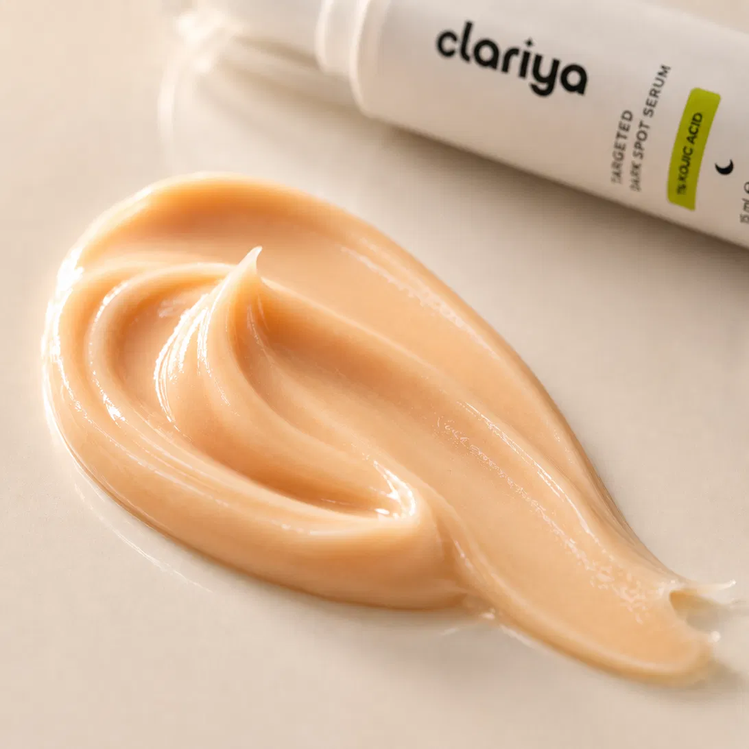 Macro close-up of the peach-to-apricot creamy CLARIYA serum swiped on a soft surface, with the bottle softly blurred behind.